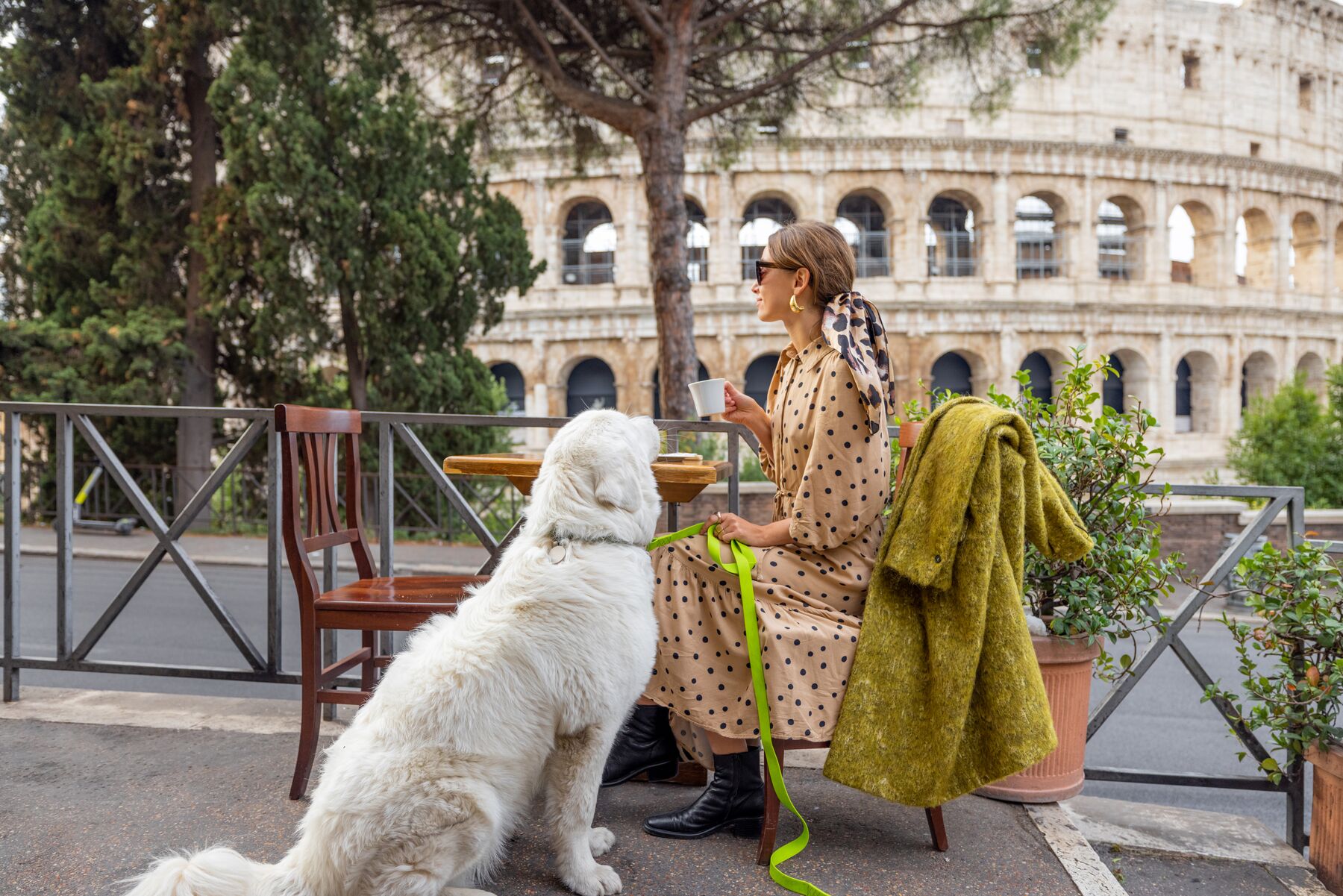 A woman sharing a coffee with her dog at an outdoor café near the Colosseum