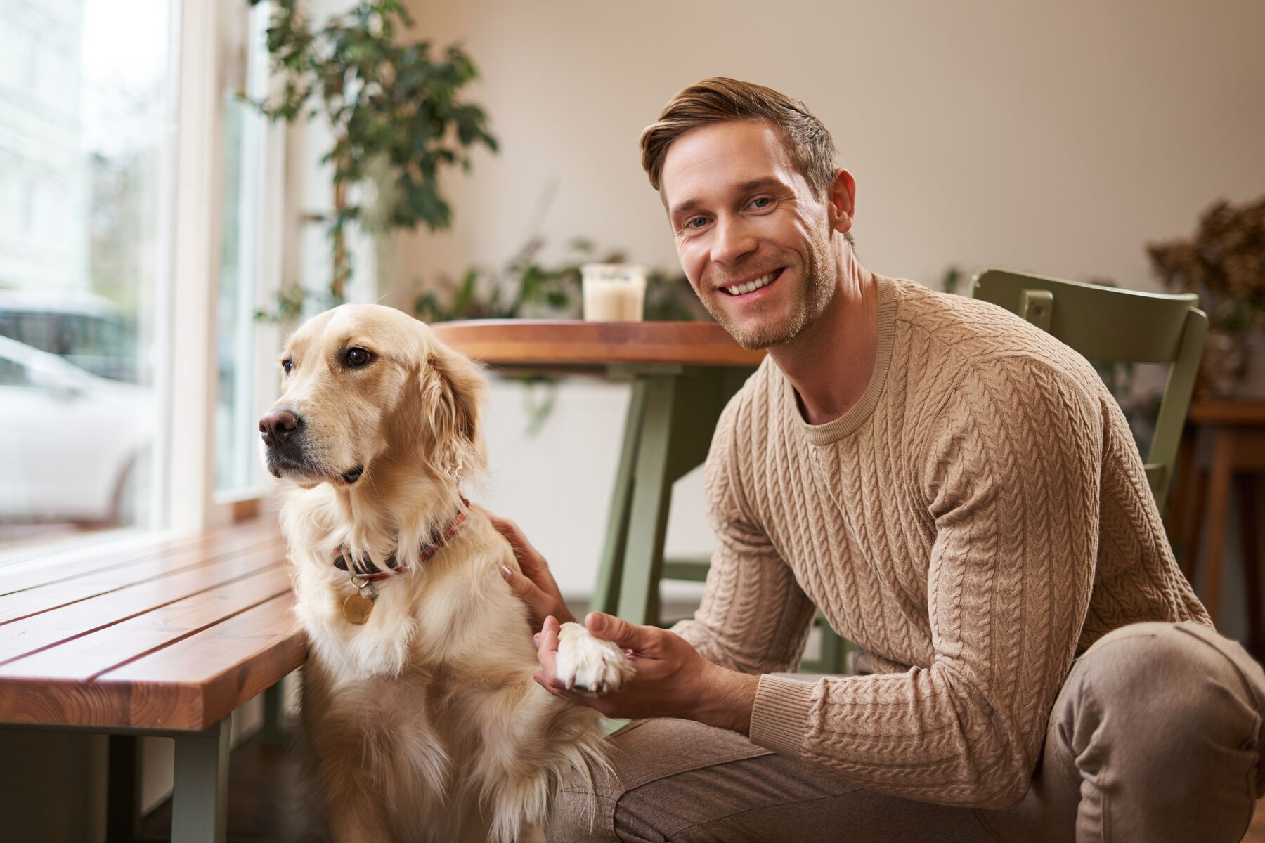 A man sharing a quiet moment with his golden retriever at a café