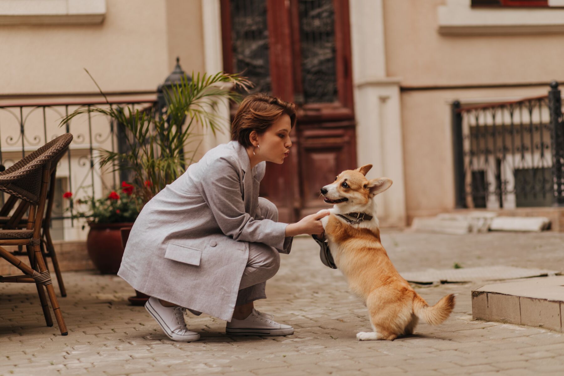 A woman greeting her corgi on a cobblestone street in Italy